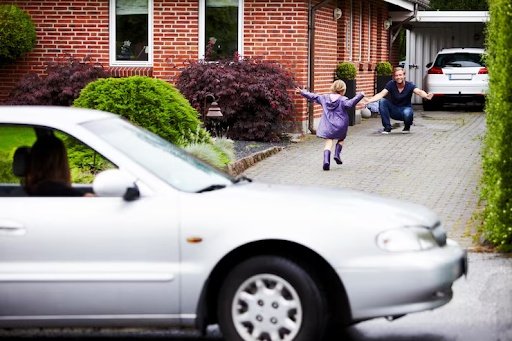 A daughter is running to hug her father while her mother watches from inside the car.
